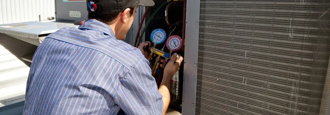 HVAC technician servicing a condenser unit in Woodland